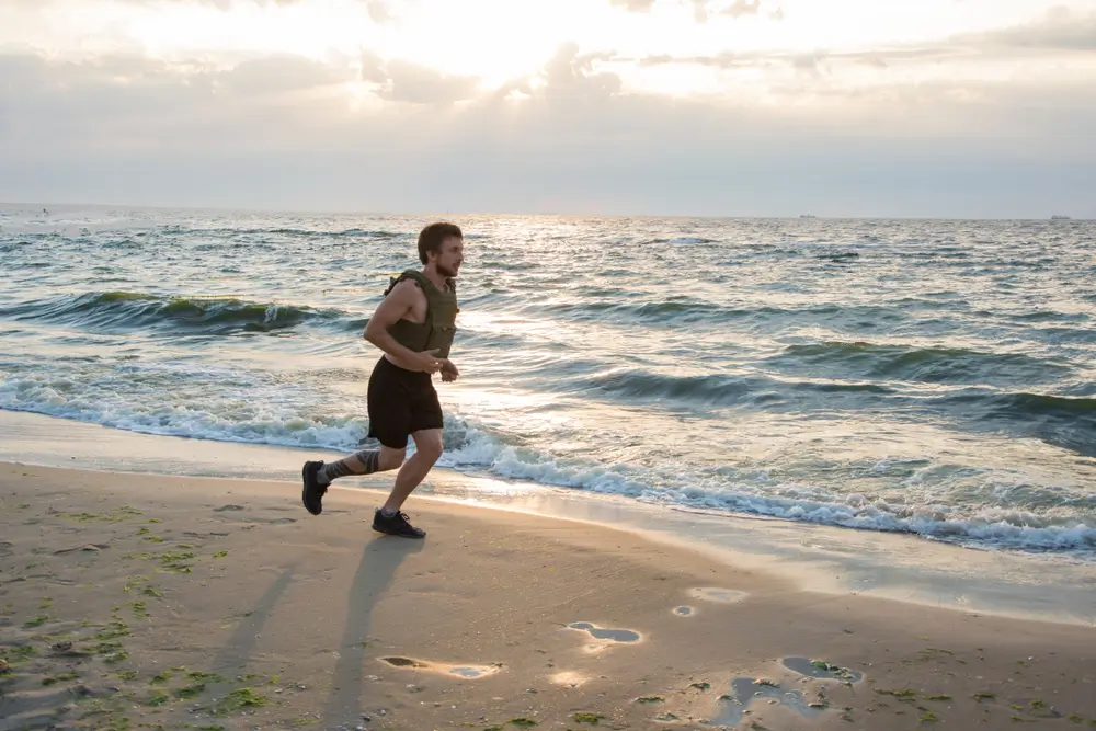 Military trainees running on a beach during special warfare physical training