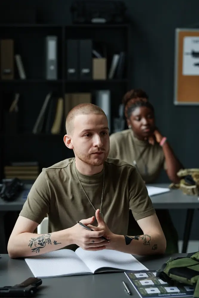 Soldiers in uniform listening to an instructor during a classroom training session