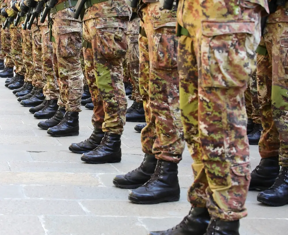 Soldiers in US Army uniforms standing in a disciplined formation on a paved military parade ground.