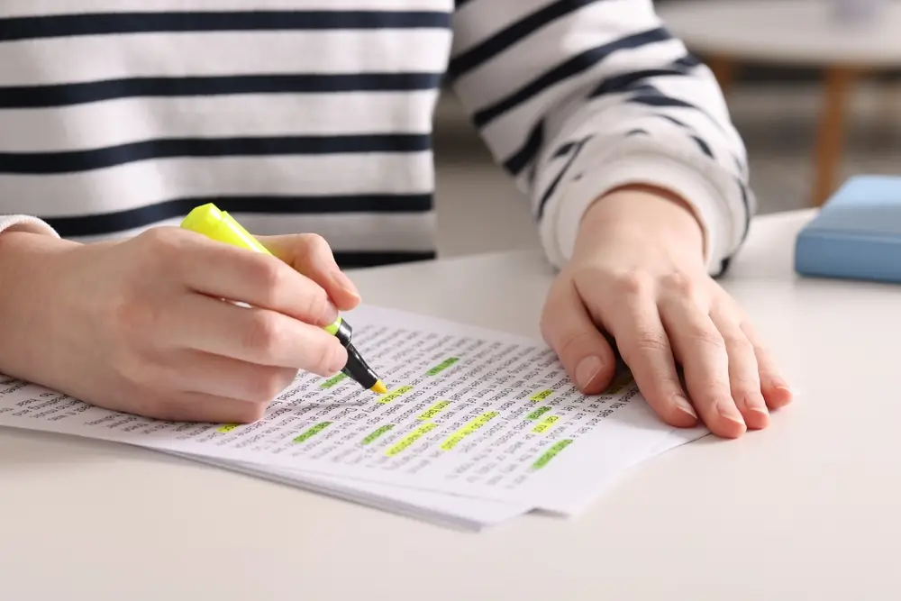 Student highlighting a textbook page while practicing vocabulary in a library