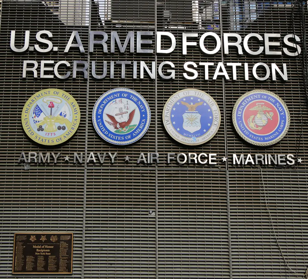 U.S. Armed Forces Recruiting Station sign with military seals for young adults taking aptitude tests.