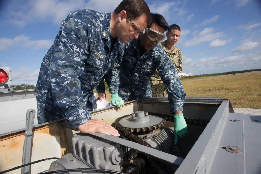 Navy technician in uniform inspecting aircraft engine components in a hangar