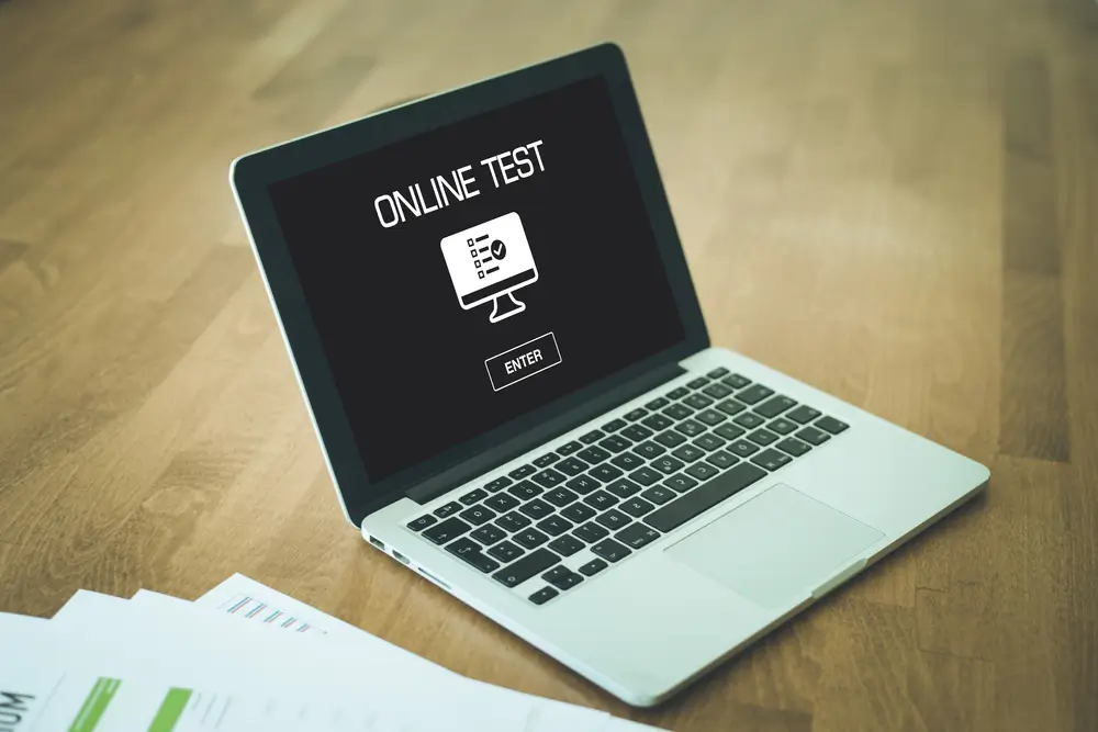 Laptop on a wooden desk displaying an online test screen for a military aptitude test computer session.
