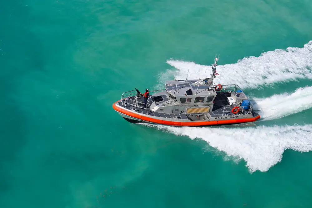 US Coast Guard patrol boat speeding across turquoise water, illustrating maritime service for prospective recruits.