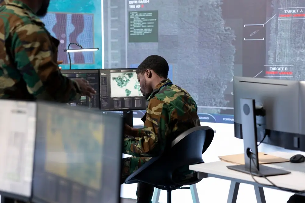 Cyber operations military specialist in uniform analyzing data on multiple screens in a command center.