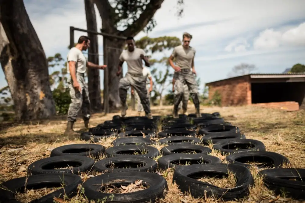 Military recruits running through a tire obstacle course during enlistment processing.